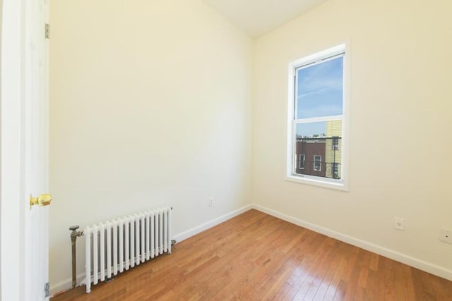 empty room featuring radiator and hardwood / wood-style floors