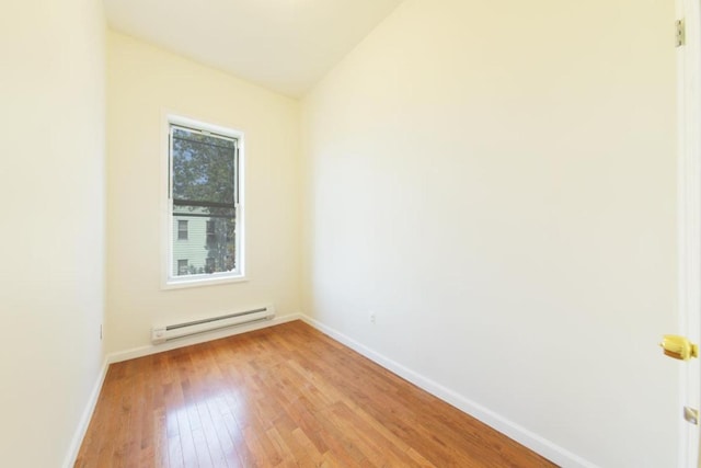 spare room with a baseboard heating unit and light hardwood / wood-style floors