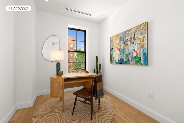 office area featuring light wood finished floors, visible vents, and baseboards