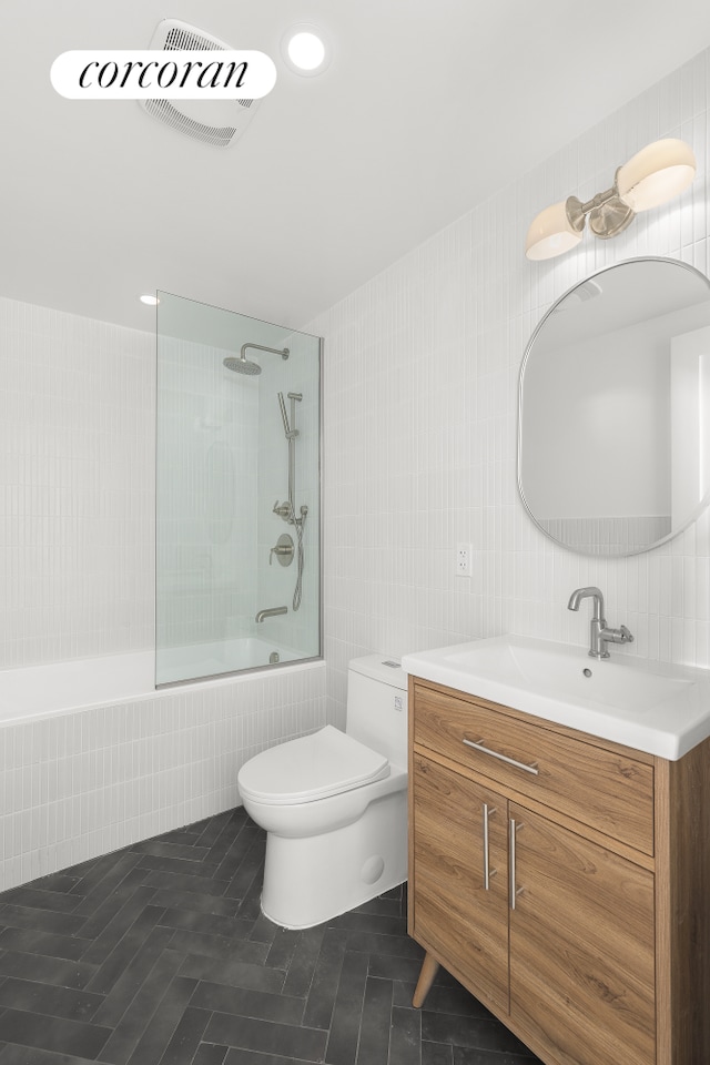 bathroom featuring toilet, bath / shower combo with glass door, visible vents, vanity, and tile patterned floors