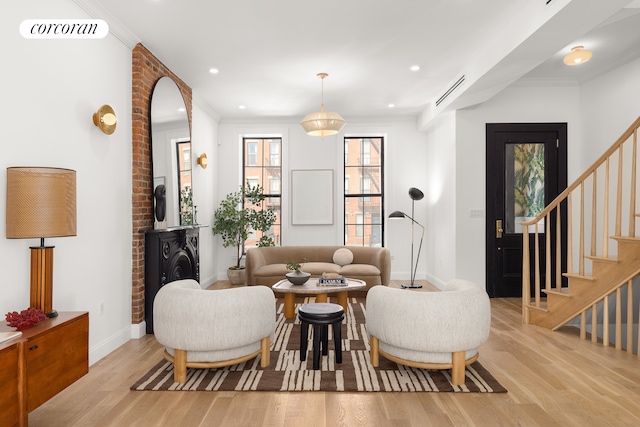 living room with light wood finished floors, visible vents, and crown molding