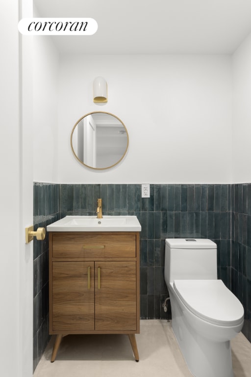 bathroom with vanity, tile walls, and toilet