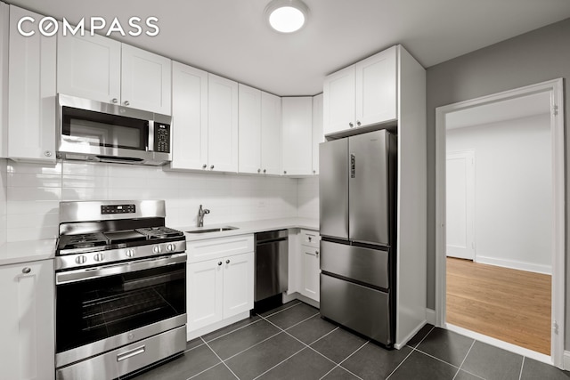 kitchen with a sink, dark tile patterned flooring, appliances with stainless steel finishes, and light countertops