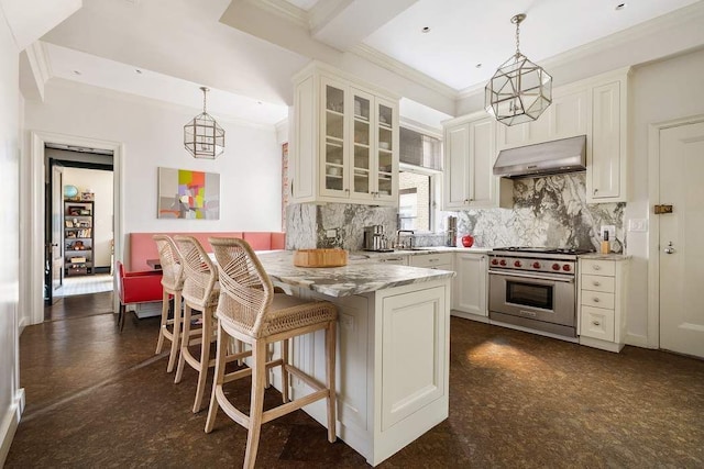 kitchen featuring a breakfast bar area, hanging light fixtures, high end stove, light stone countertops, and decorative backsplash