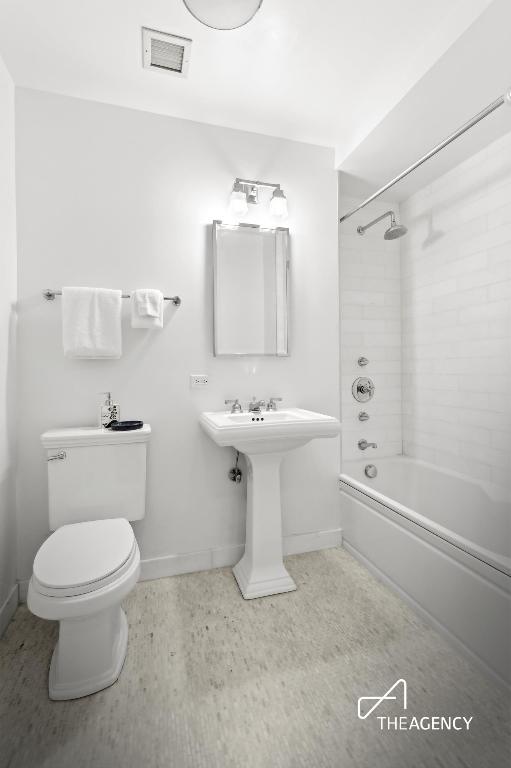 bathroom featuring toilet and tiled shower / bath