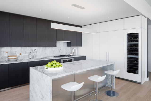 kitchen with pendant lighting, sink, light hardwood / wood-style floors, and a kitchen island