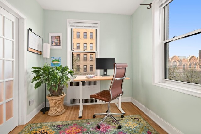 office space featuring radiator and light hardwood / wood-style flooring