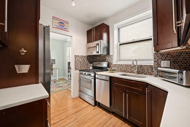 kitchen with sink, light hardwood / wood-style flooring, backsplash, dark brown cabinets, and stainless steel appliances