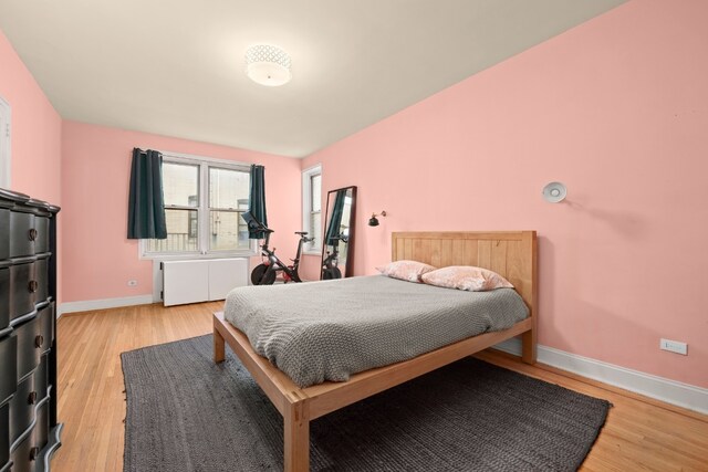 bedroom with radiator heating unit and light hardwood / wood-style flooring