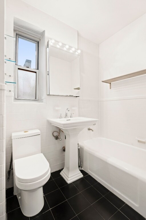 bathroom with sink, tile walls, tile patterned floors, and toilet