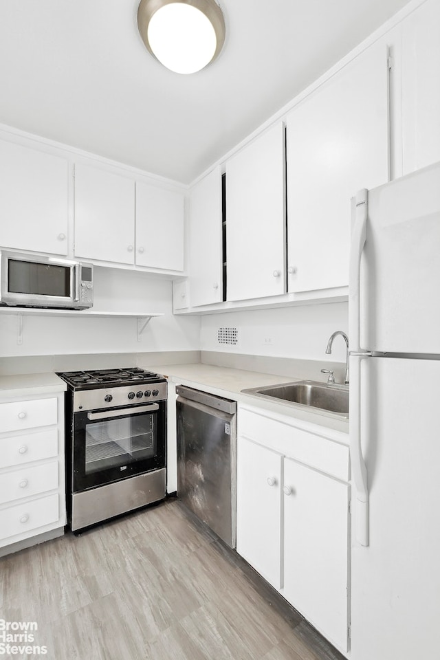 kitchen with light countertops, white cabinets, appliances with stainless steel finishes, and a sink