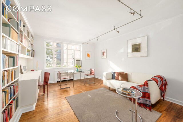 living area with wood-type flooring, rail lighting, and ornamental molding