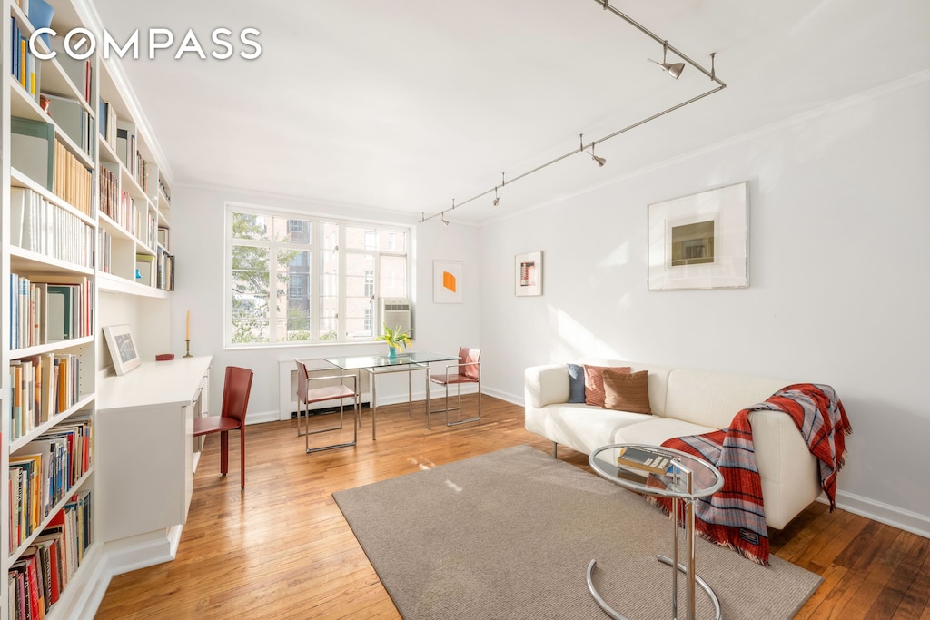 sitting room with baseboards, hardwood / wood-style floors, track lighting, and crown molding