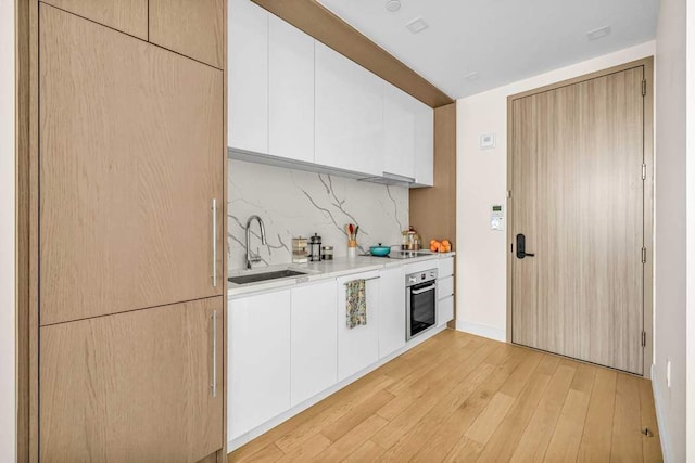 kitchen featuring sink, stainless steel oven, white cabinets, and black electric cooktop