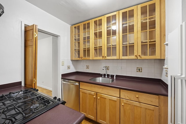 kitchen with freestanding refrigerator, dark countertops, tasteful backsplash, a sink, and dishwasher