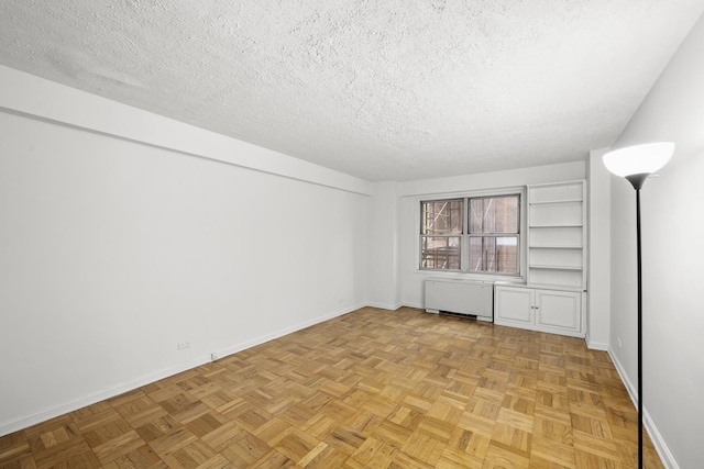 unfurnished room featuring radiator, a textured ceiling, and baseboards