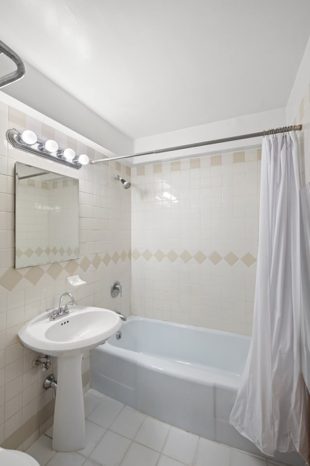 full bath with shower / bath combo with shower curtain, tile patterned floors, and tile walls