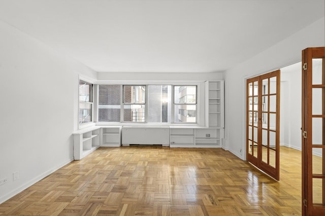 empty room with french doors, baseboards, and radiator heating unit