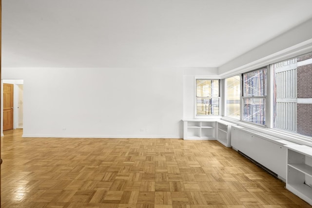 unfurnished room featuring baseboards and radiator