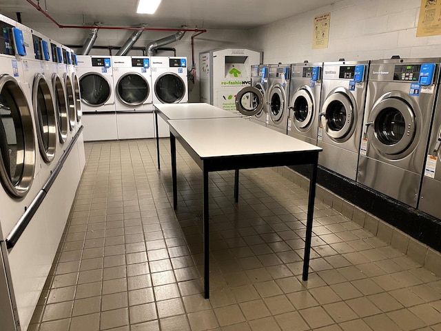 community laundry room featuring washing machine and dryer and concrete block wall