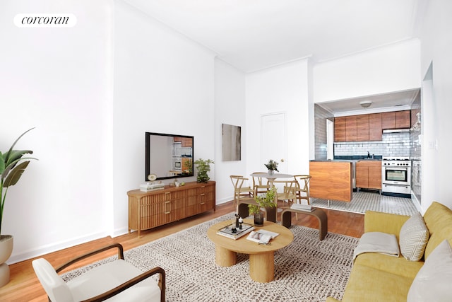 living room with baseboards, visible vents, a high ceiling, and light wood-style floors