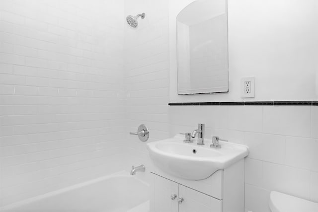 bathroom with a wainscoted wall, tile walls, shower / bathtub combination, toilet, and vanity