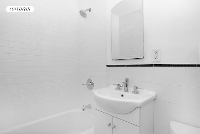 full bathroom featuring bathing tub / shower combination, vanity, toilet, and tile walls