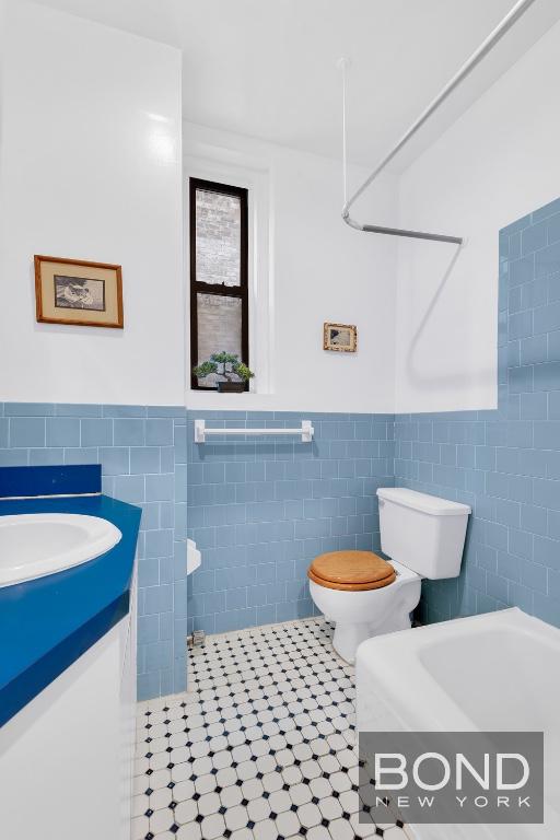 bathroom with tile walls, vanity, tile patterned floors, and toilet