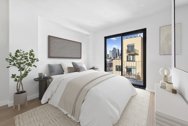 bedroom with access to exterior, a fireplace, baseboards, and light wood-style floors