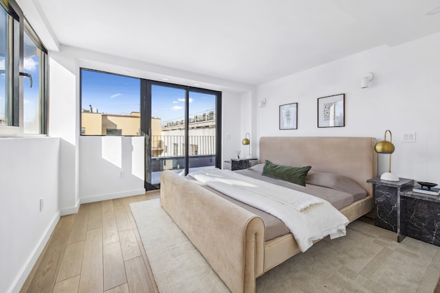 bedroom featuring baseboards, light wood finished floors, and access to outside