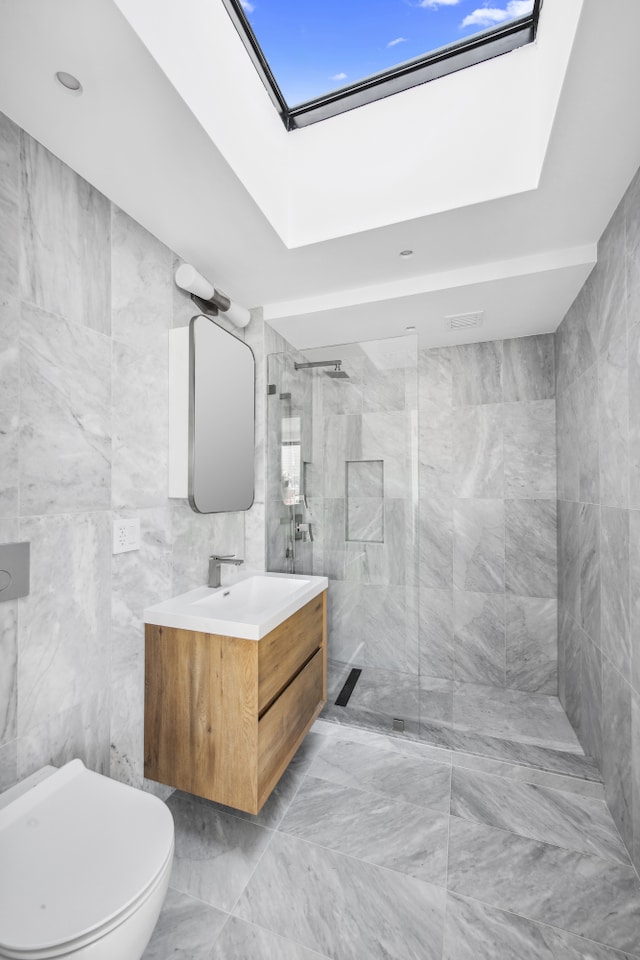 bathroom with vanity, a skylight, a walk in shower, tile walls, and marble finish floor