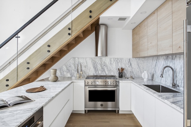 kitchen with sink, backsplash, white cabinets, high end range, and light stone counters