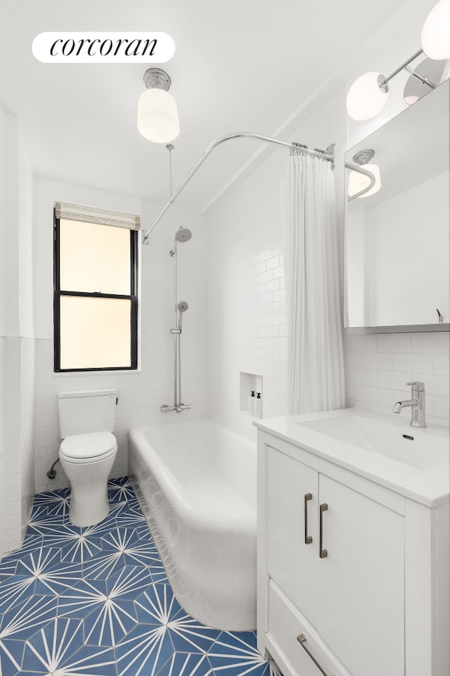 bathroom with tile patterned flooring, toilet, shower / tub combo, vanity, and tile walls