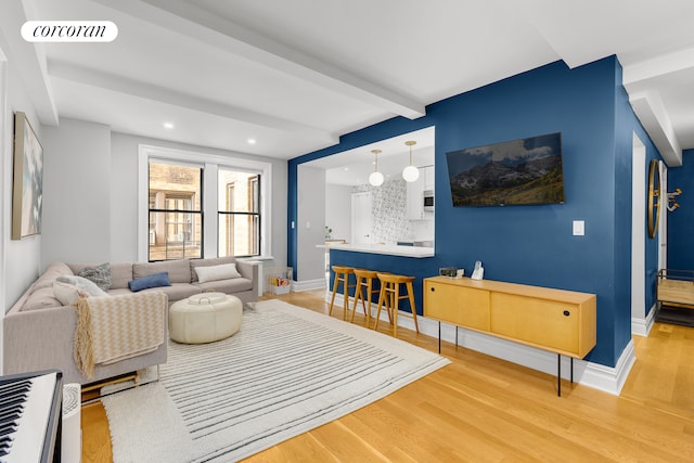 living room featuring beamed ceiling, light wood-type flooring, visible vents, and baseboards