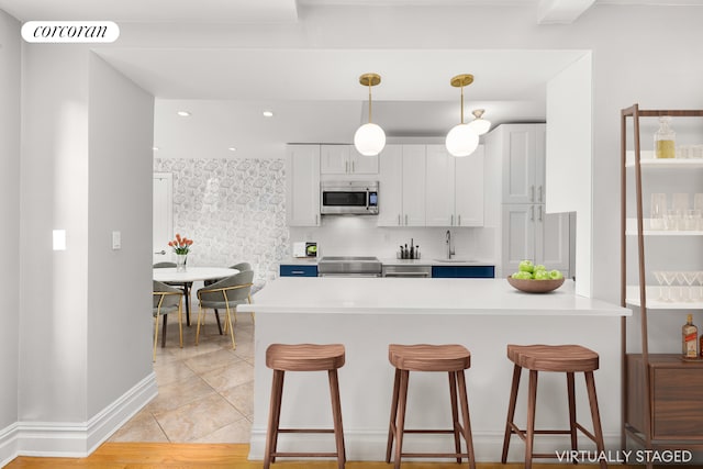 kitchen with stainless steel appliances, a breakfast bar, a sink, light countertops, and recessed lighting