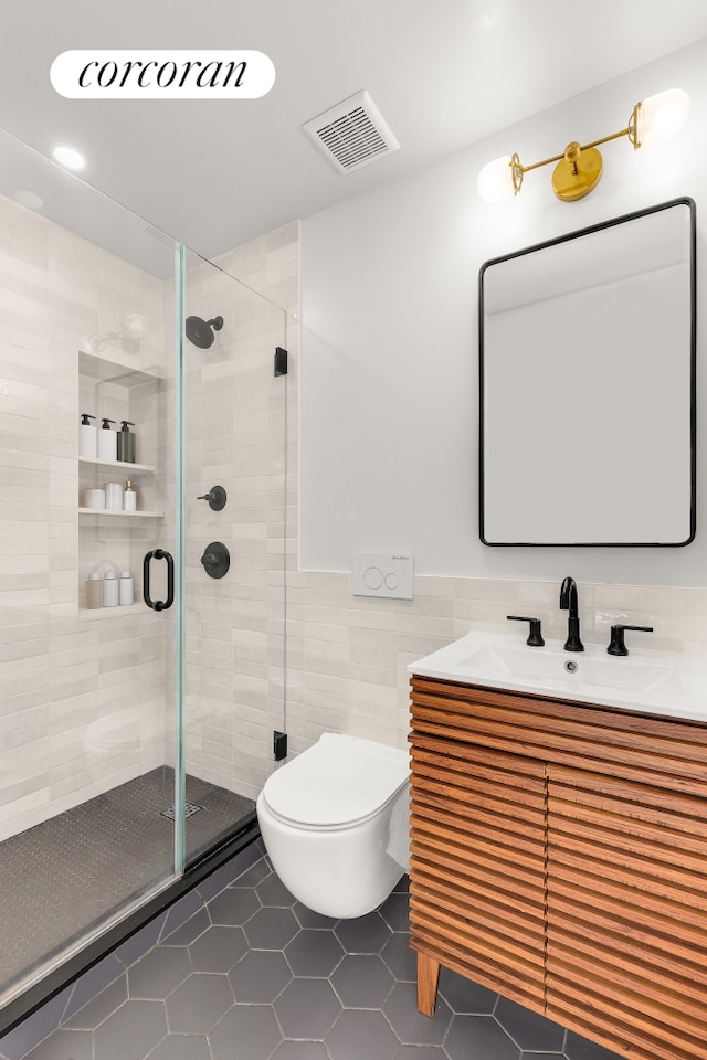 bathroom featuring tile patterned flooring, toilet, a stall shower, vanity, and tile walls