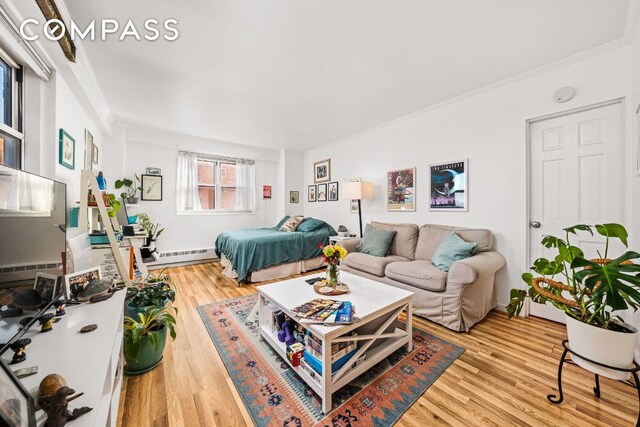 bedroom featuring hardwood / wood-style floors, ornamental molding, and baseboard heating