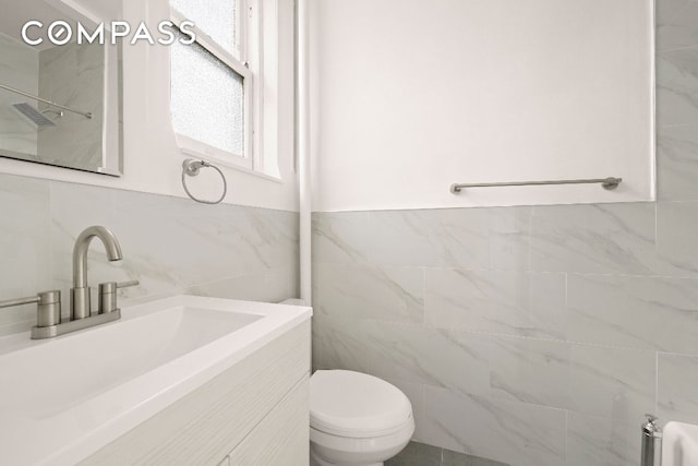 bathroom featuring tile walls, vanity, and toilet