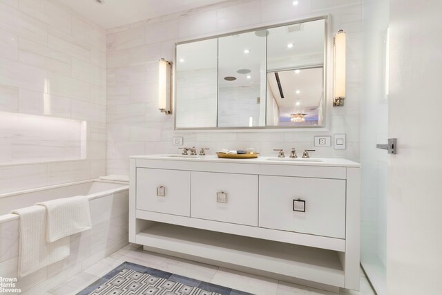 bathroom featuring tile patterned flooring, tile walls, vanity, and a relaxing tiled tub