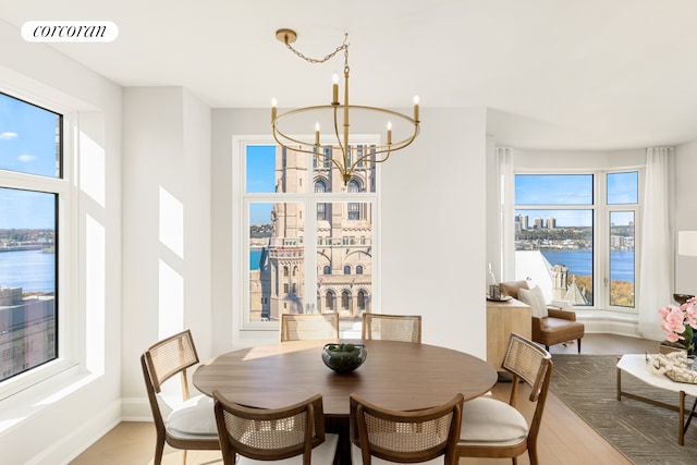 dining room featuring light wood finished floors, plenty of natural light, visible vents, and an inviting chandelier