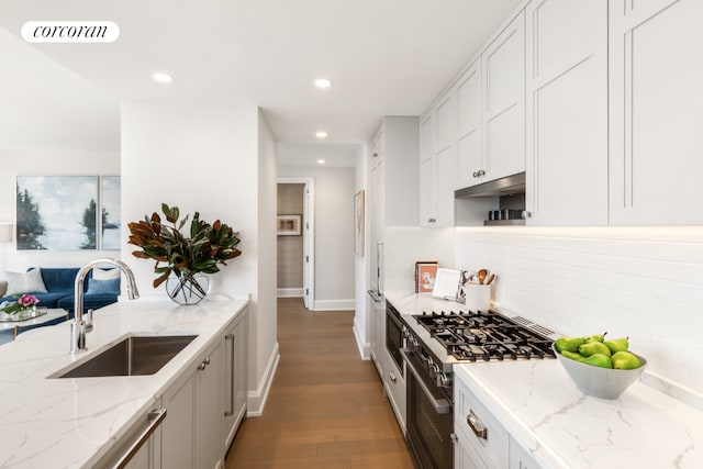 kitchen with visible vents, decorative backsplash, light stone counters, high end stainless steel range, and a sink