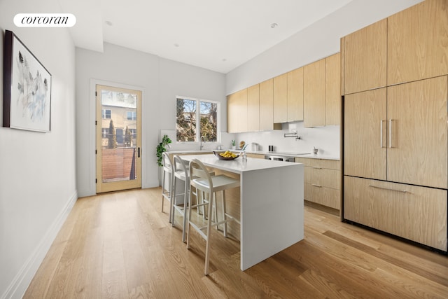 kitchen with light brown cabinets, a breakfast bar, light wood-style floors, light countertops, and modern cabinets