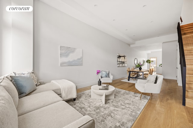 living room with stairway, light wood-style flooring, and baseboards