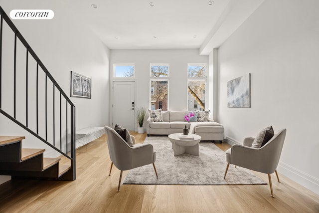 living area featuring visible vents, stairway, light wood-style flooring, and baseboards