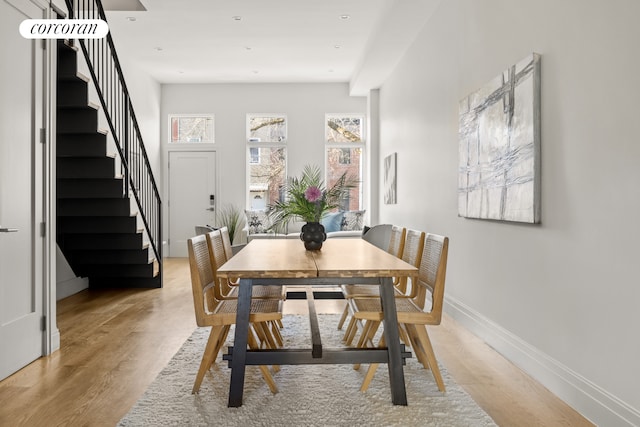 dining room featuring stairway, light wood-style floors, and baseboards