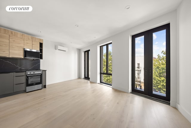 kitchen with wall oven, stainless steel microwave, modern cabinets, and a wall unit AC