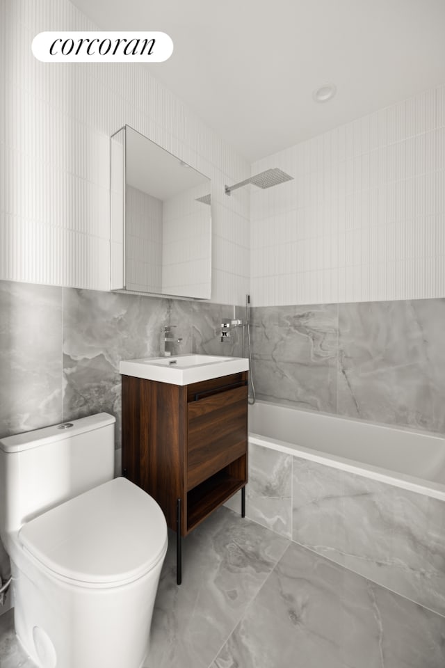 bathroom featuring vanity, tile walls, toilet, tiled shower / bath, and marble finish floor