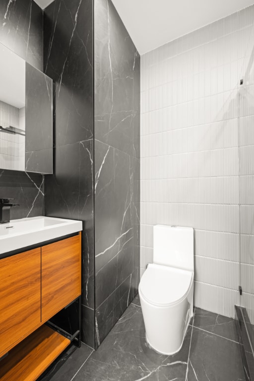 bathroom featuring vanity, tile walls, and toilet