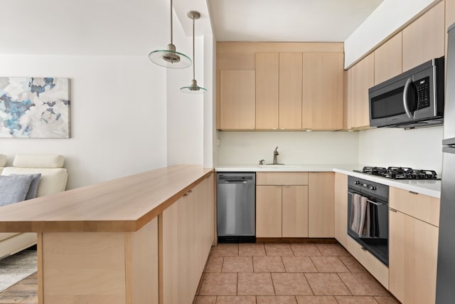 kitchen with hanging light fixtures, stainless steel appliances, sink, and light brown cabinets