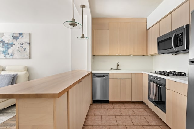 kitchen with a sink, stainless steel appliances, a peninsula, and light brown cabinets